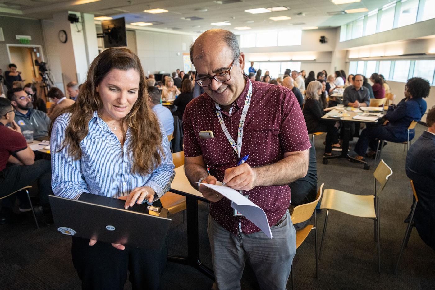 two people who attended a gathering looking at a laptop